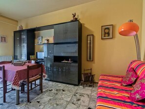 A compact living space with a dining area, kitchenette, and a sofa with a colorful blanket. - Il Broletto B&B (Novara)