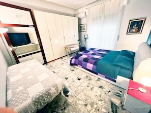Un dormitorio con cama, armario, televisor y equipo de ejercicio.