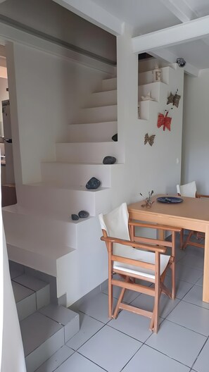 A dining area with a wooden table and chairs, a staircase with decorative rocks, and a security camera. - Country House 'The Arch House' with Sea View (Κύμη)