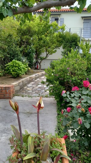 A garden with a variety of plants, a brick wall, and a pathway leading to a building. - Country House 'The Arch House' with Sea View (Κύμη)