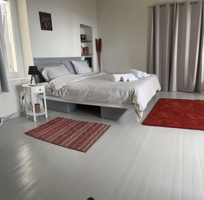 A modern bedroom with a bed, bedside tables, a red rug, and a grey curtain. - Country House 'The Arch House' with Sea View (Κύμη)
