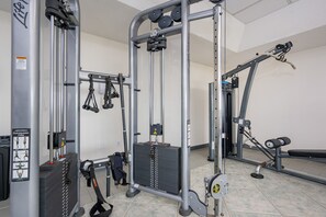 A gym with various exercise equipment, including a cable machine, a squat rack, and weight plates. - Phoenix Vi 6707 1 Bedroom Condo (Orange Beach)