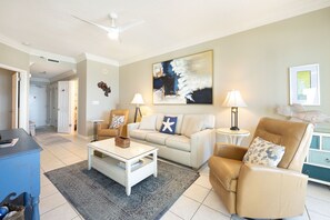 A living room with a white sofa, a beige armchair, a coffee table, and a floor lamp. - Phoenix Vi 61402 1 Bedroom Condo (Orange Beach)
