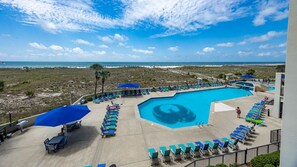 A pool area with lounge chairs and umbrellas, overlooking a beach and ocean. - Phoenix Vi 6212 2 Bedroom Condo (Orange Beach)