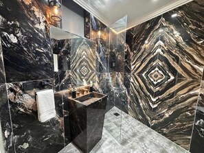 Ein modernes Badezimmer mit Marmorverkleidung, einem Waschbecken und einem Spiegel.