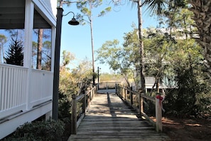 A wooden deck leading to a building with a white exterior and a metal railing. - SEAS THE DAY IS A PRIVATE 2BD COTTAGE WITH 3 COMMUNITY POOLS, PET FRIENDLY! (Port Saint Joe)
