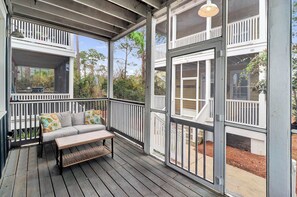 A covered porch with a bench and railing, large windows, and a view of the outdoors. - SEAS THE DAY IS A PRIVATE 2BD COTTAGE WITH 3 COMMUNITY POOLS, PET FRIENDLY! (Port Saint Joe)