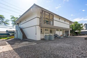 A two-story building with a balcony, a staircase, and a gravel driveway. - Big Island Kahaluu Surf Boutique #5 2 Bedroom Apts (Kailua-Kona)
