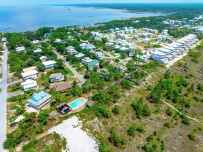 Vista aérea de uma área residencial costeira com casas, piscina e praia.