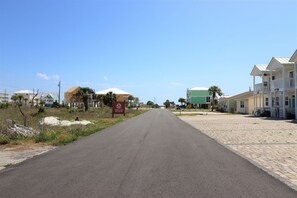 A road leading to a residential area with houses and a sign indicating a property is coming soon. - PELICAN PERCH IS A 3BD/2BA  TOWNHOUSE JUST STEPS TO BEACH AND SHOPS! (Mexico Beach)