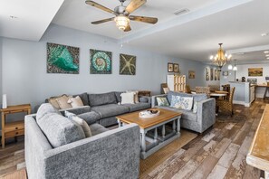 A spacious living room with a sectional sofa, a wooden coffee table, and a ceiling fan. - The Club at Mexico Beach, panoramic gulf views, steps to the beach, community po (Mexico Beach)