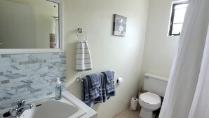 Un bagno con lavandino bianco, uno specchio, un water e una tenda da doccia.