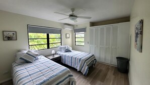 Una camera da letto con due letti, una ventola a soffitto e vista sul verde circostante.