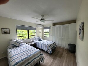 A bedroom with two beds, a ceiling fan, and a view of greenery outside. - Modern 2 bed 2 bath home away from home perfectly located for visitors (Bridgetown)