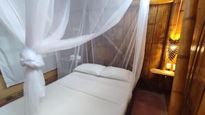 A single bed with a white canopy, a bedside table with a lamp, and a wooden wall. - Jui Chi MaMa Ecolodge & Birding (PALOMINO)
