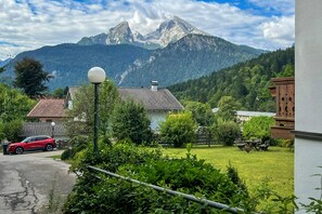 Un quartier résidentiel avec des maisons, une voiture garée et une chaîne de montagnes en arrière-plan.