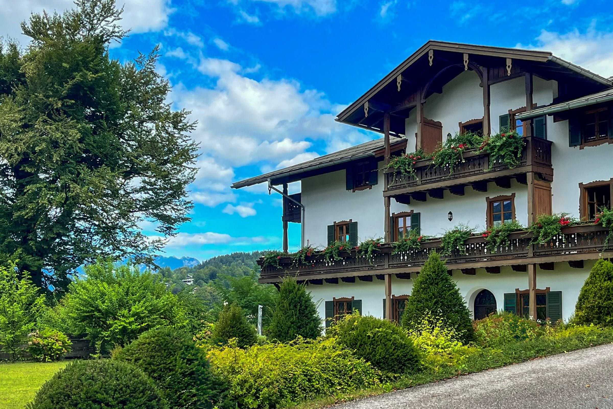 Ein mehrstöckiges Gebäude mit Balkonen, umgeben von üppiger Vegetation und blauem Himmel.