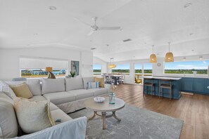 Uma sala de estar ampla com um sofá grande, uma mesa de jantar e uma cozinha com banquetas.