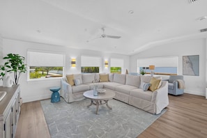 A modern living room with a sectional sofa, a coffee table, and a view of the outdoors. - Riverfront Retreat | Dock & River Access | Kayak (St. Augustine)