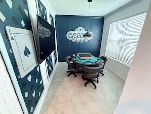 A room with a poker table, chairs, and a wall with poker card designs. - Heated Pool · Home Theater · Game Room · Sleeps 18 (Melbourne Beach)