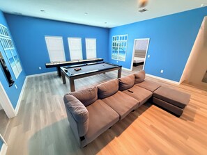 A room with a pool table, a sofa, and a bed with a view. - Heated Pool · Home Theater · Game Room · Sleeps 18 (Melbourne Beach)