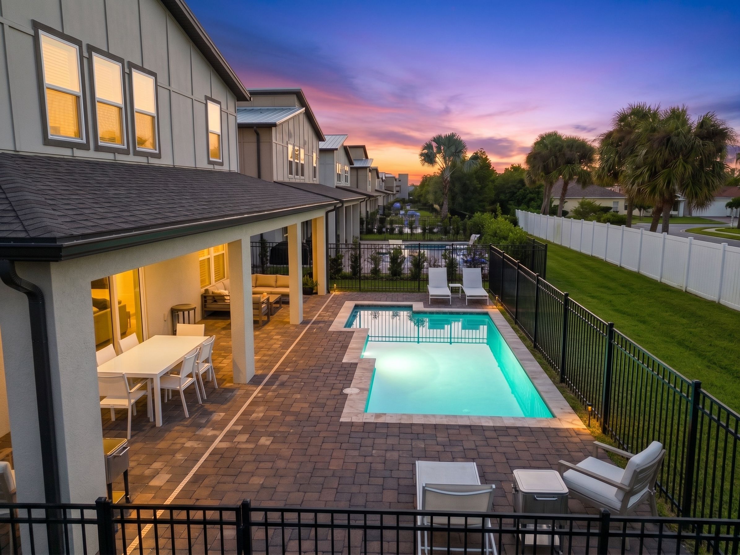 A residential property with a swimming pool, outdoor seating, and a view of the neighborhood.