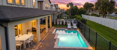 A residential property with a swimming pool, outdoor seating, and a view of the neighborhood.