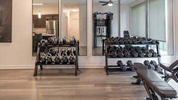 A home gym with kettlebells, dumbbells, and a bench.