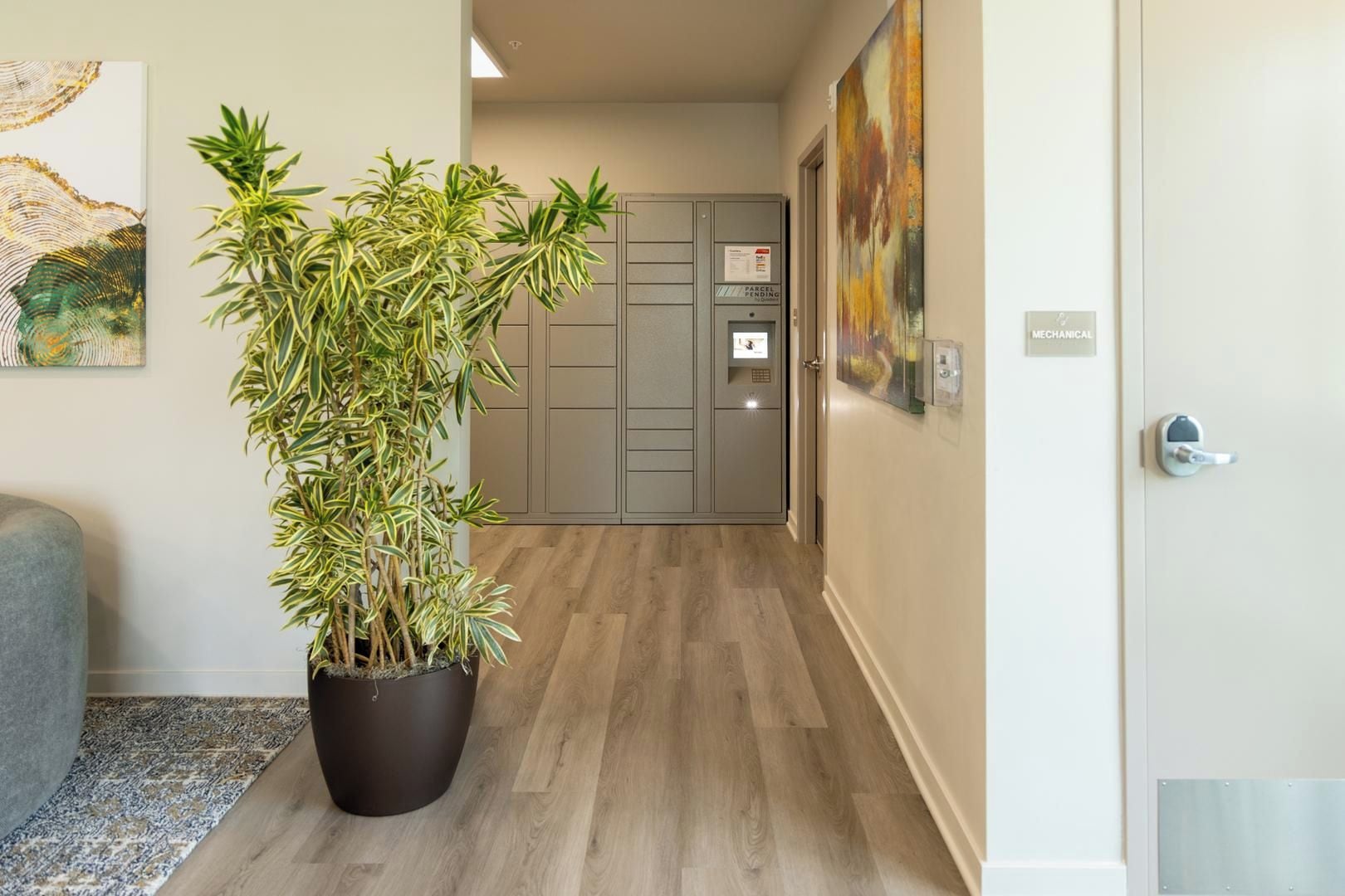 A hallway with a potted plant, a door with a 'Mechanical' sign, and a 'Parcel Pending' sign on a grey cabinet.
