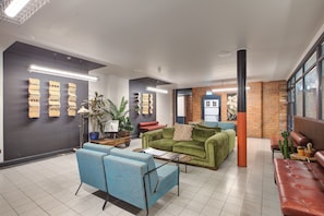 Eine moderne Lobby mit Sitzbereichen, einem Couchtisch und dekorativer Wandgestaltung.