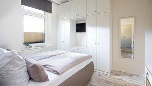 A bedroom with a bed, a window, and a wardrobe. - Vrbo Property (Norderney)