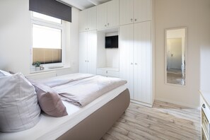 Ein Schlafzimmer mit Bett, Fenster und Kleiderschrank.