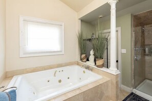 A bathroom with a bathtub, a shower, and a window with blinds. - The General - Historic Pensacola Apt with Pool & Spa (Pensacola)