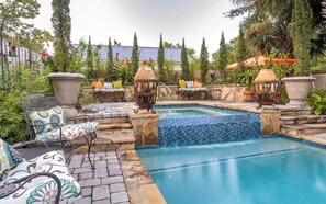 A swimming pool with a tiled edge, surrounded by stone steps, and furnished with outdoor seating. - The General - Historic Pensacola Apt with Pool & Spa (Pensacola)