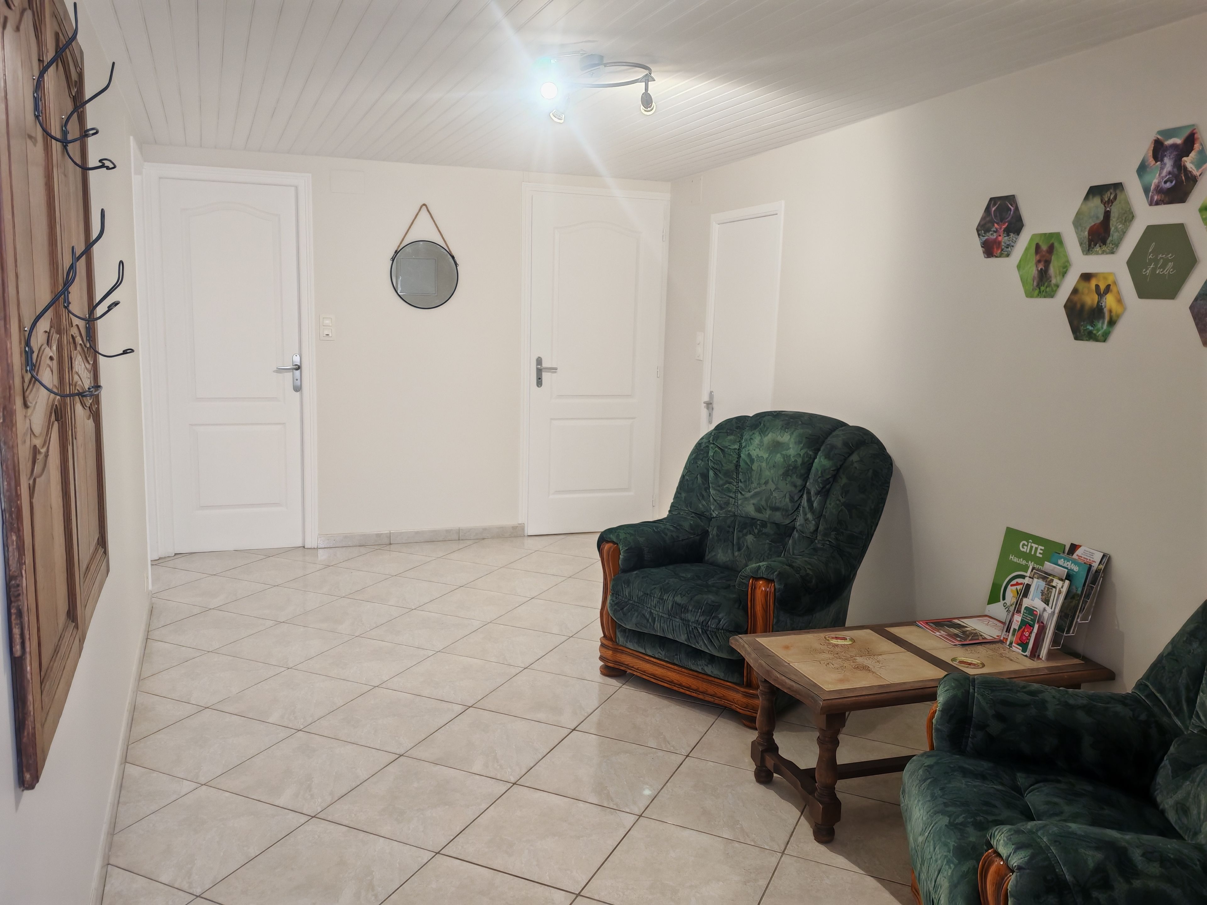 A room with a green armchair, a wooden coffee table, and a wall with hexagonal animal prints.