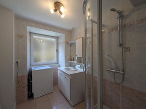 A bathroom with a shower, a sink, and a window. - Vrbo Property (Châteauvillain)