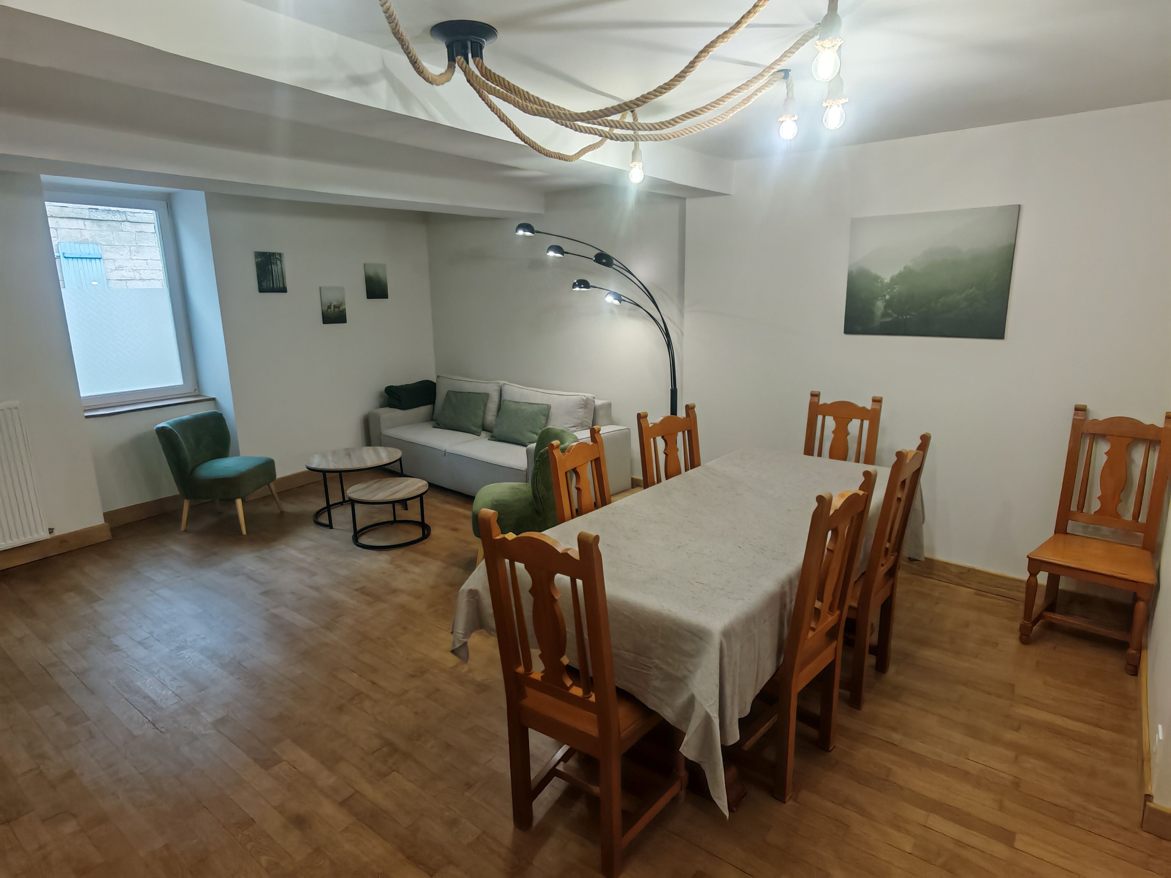 A dining area with a table and chairs, a sofa, a lamp, and a window.