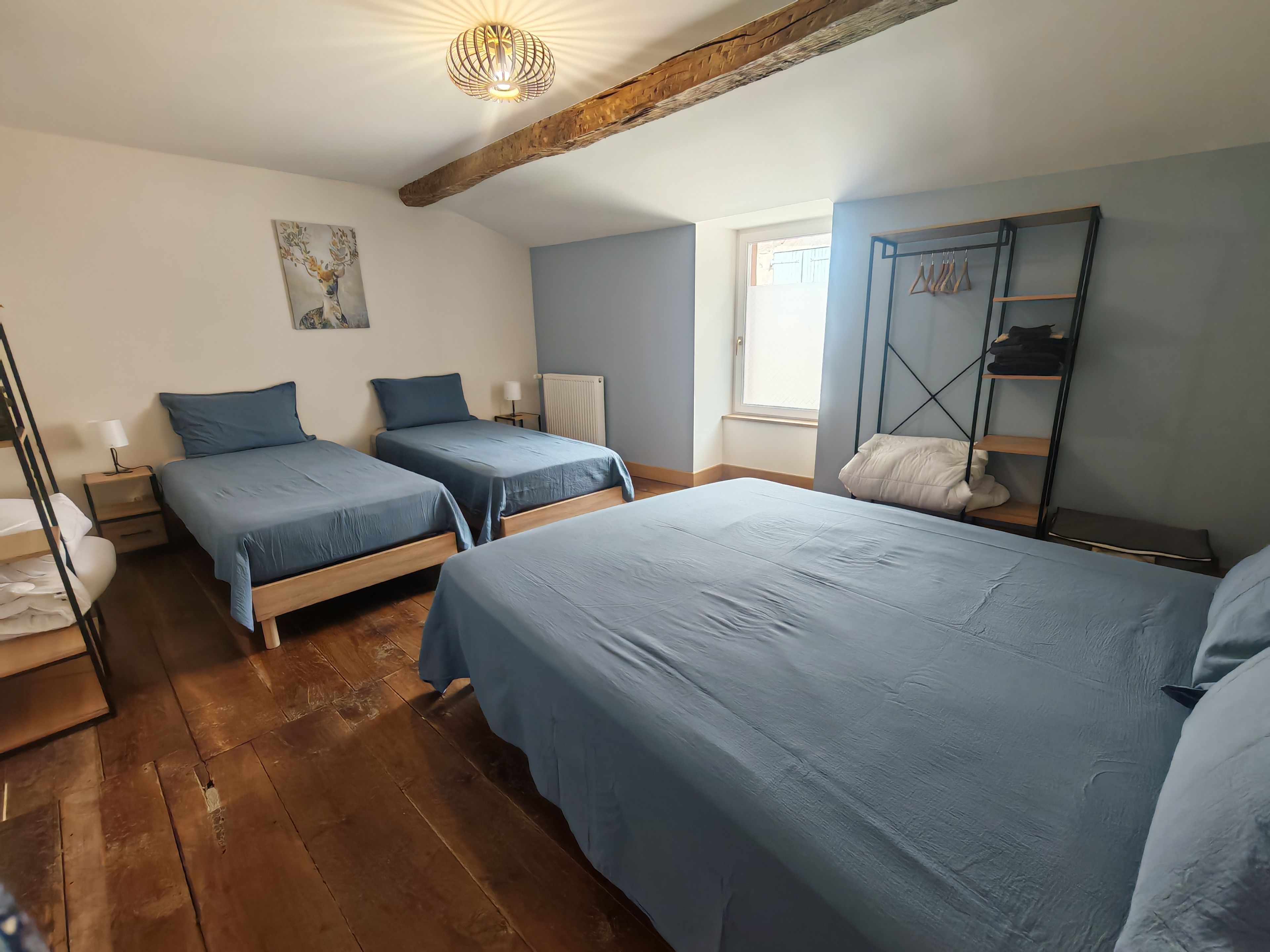 Ein Schlafzimmer mit zwei Betten, Holzboden, Heizkörper, Fenster und einem Kleiderschrank.
