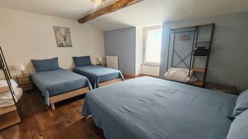 Ein Schlafzimmer mit zwei Betten, Holzboden, Heizkörper, Fenster und einem Kleiderschrank.