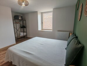 A bedroom with a bed, a radiator, a window, and a wardrobe. - Vrbo Property (Châteauvillain)