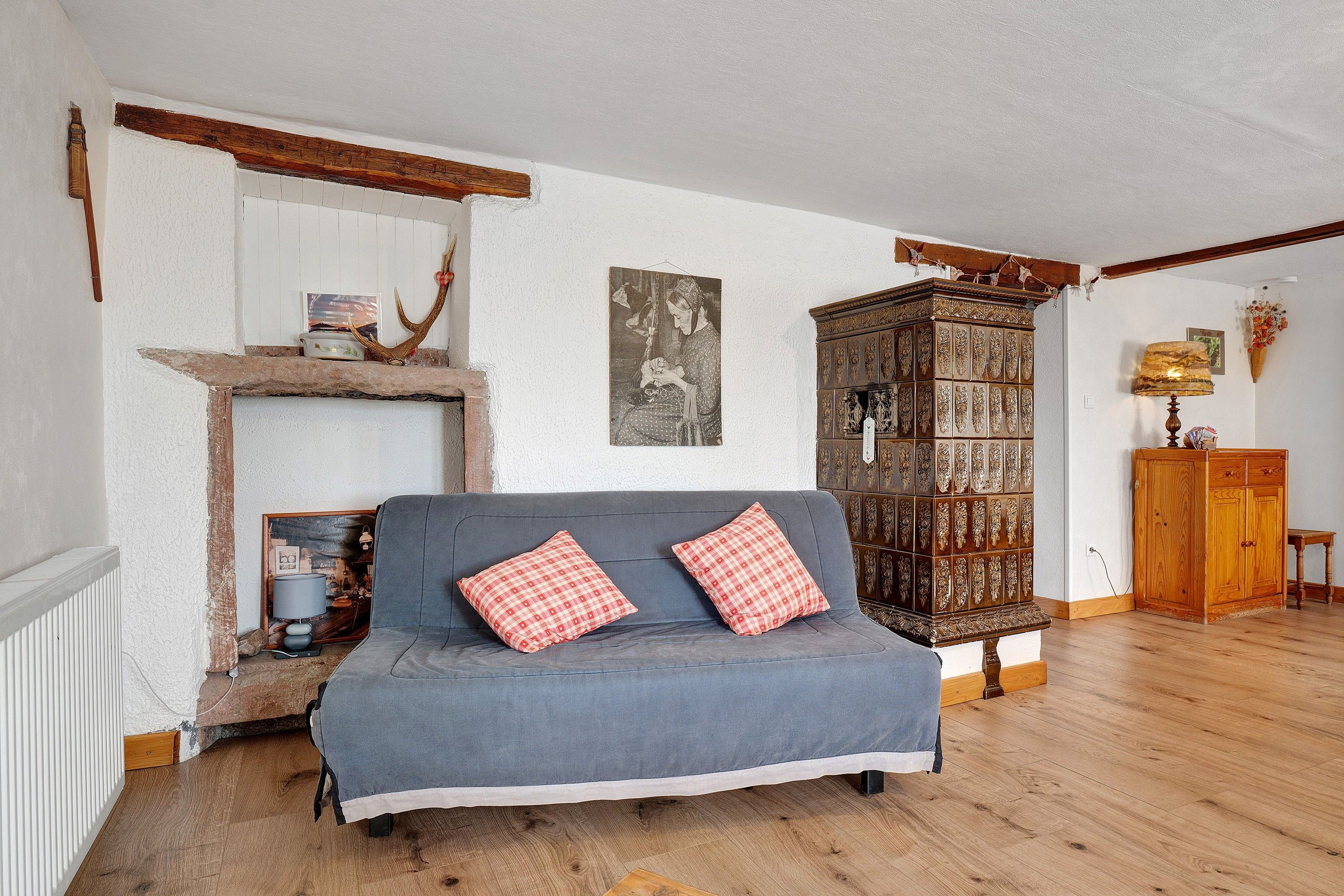 Un salon chaleureux avec un canapé bleu, un meuble en bois et une cheminée.
