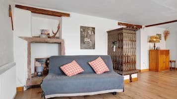 Een gezellige woonkamer met een blauwe bank, een houten kast en een open haard.