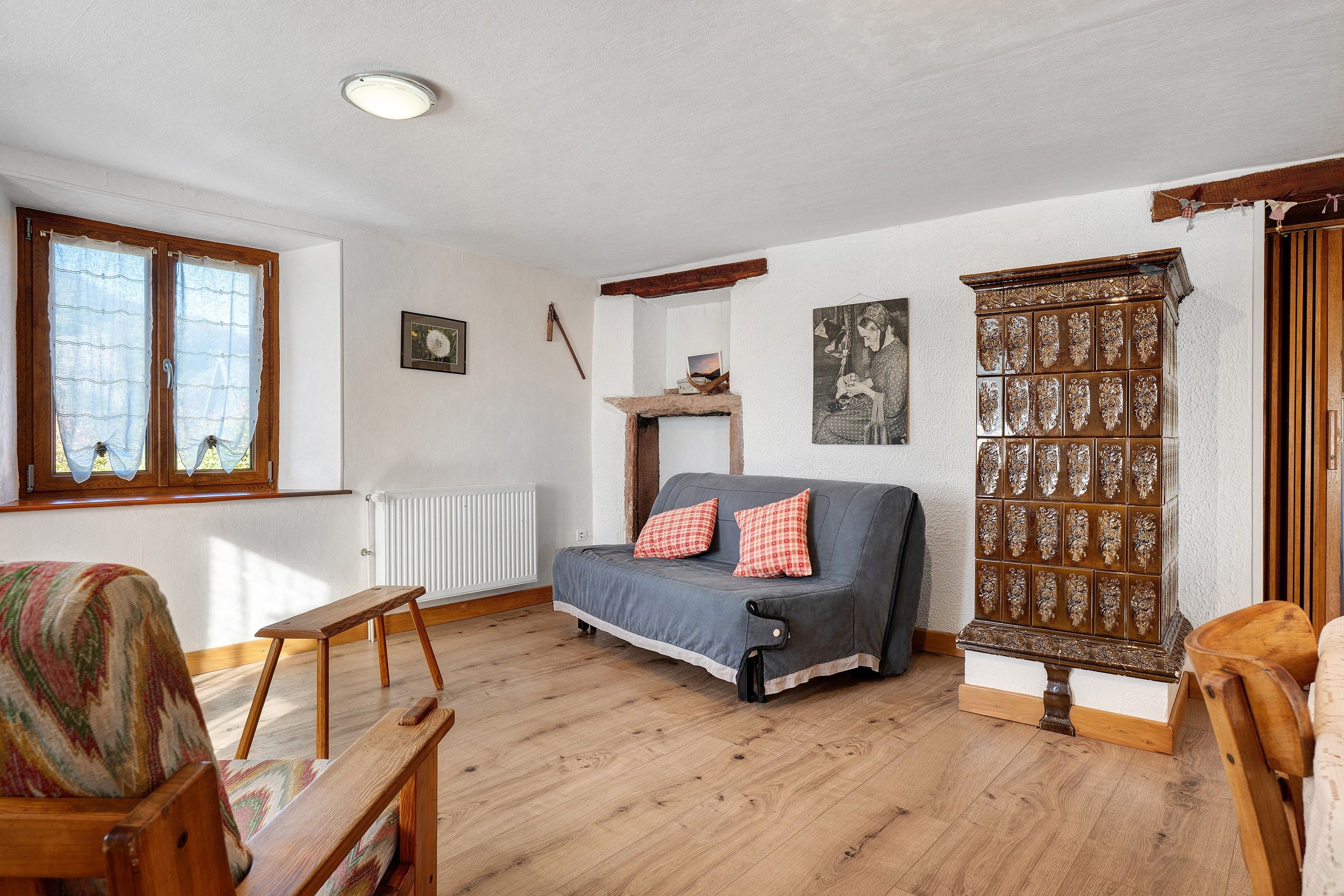 A cozy living room with a sofa, a wooden bench, a radiator, and a decorative cabinet.