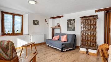 A cozy living room with a sofa, a wooden bench, a radiator, and a decorative cabinet.