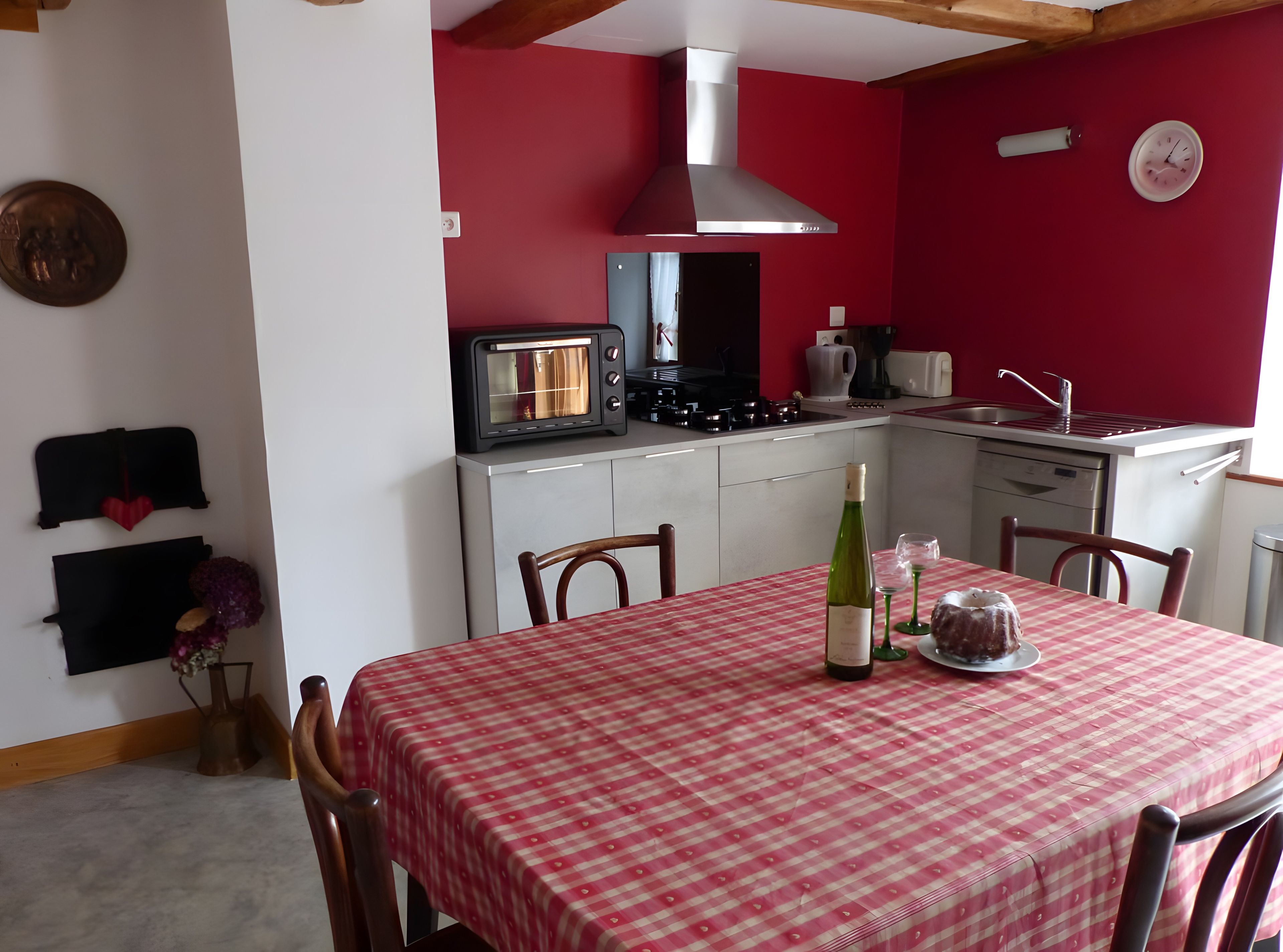 A compact kitchen with a red wall, a built-in oven, a microwave, and a sink.