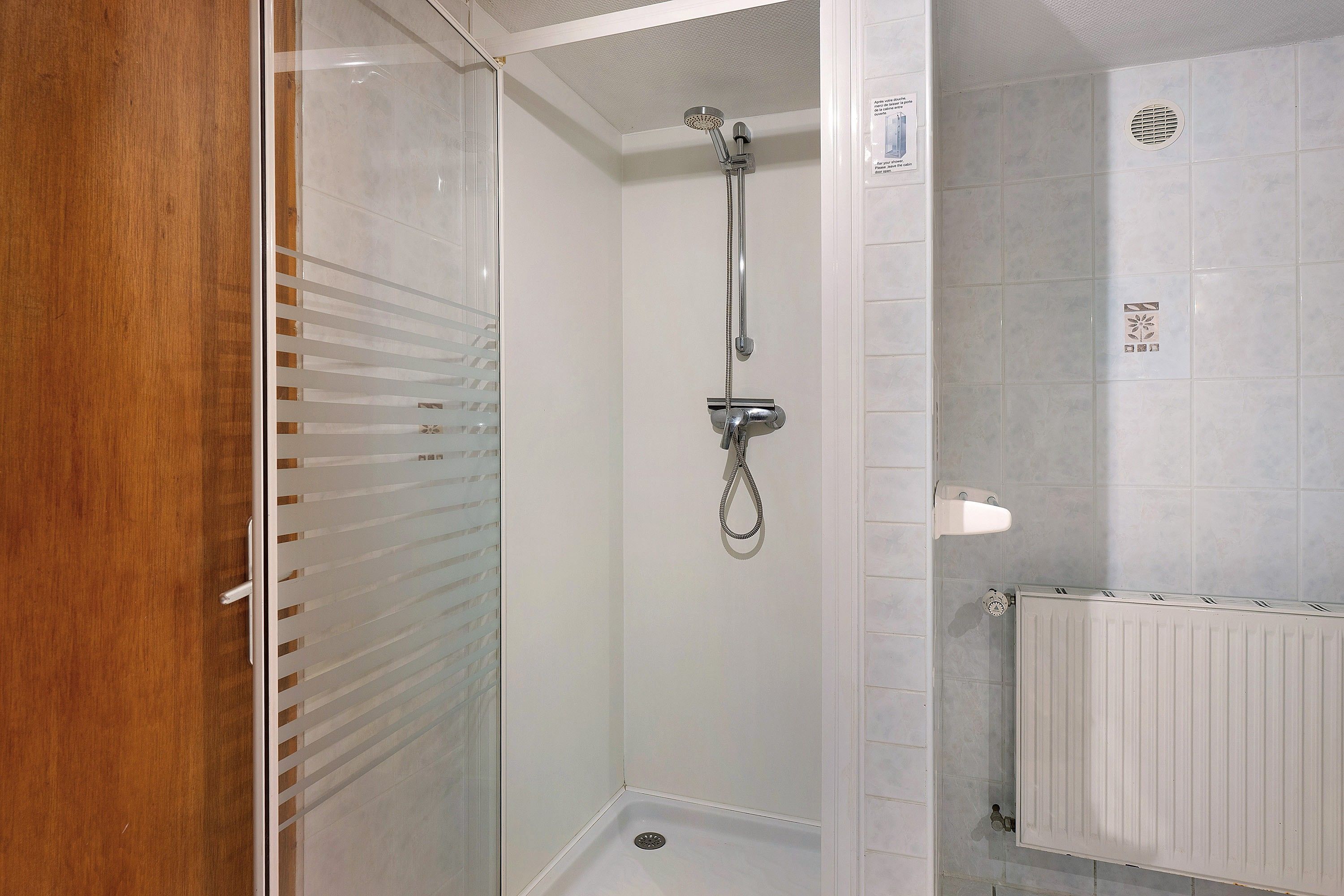 Une douche équipée d’un pommeau de douche à main et d’un robinet fixé au mur.