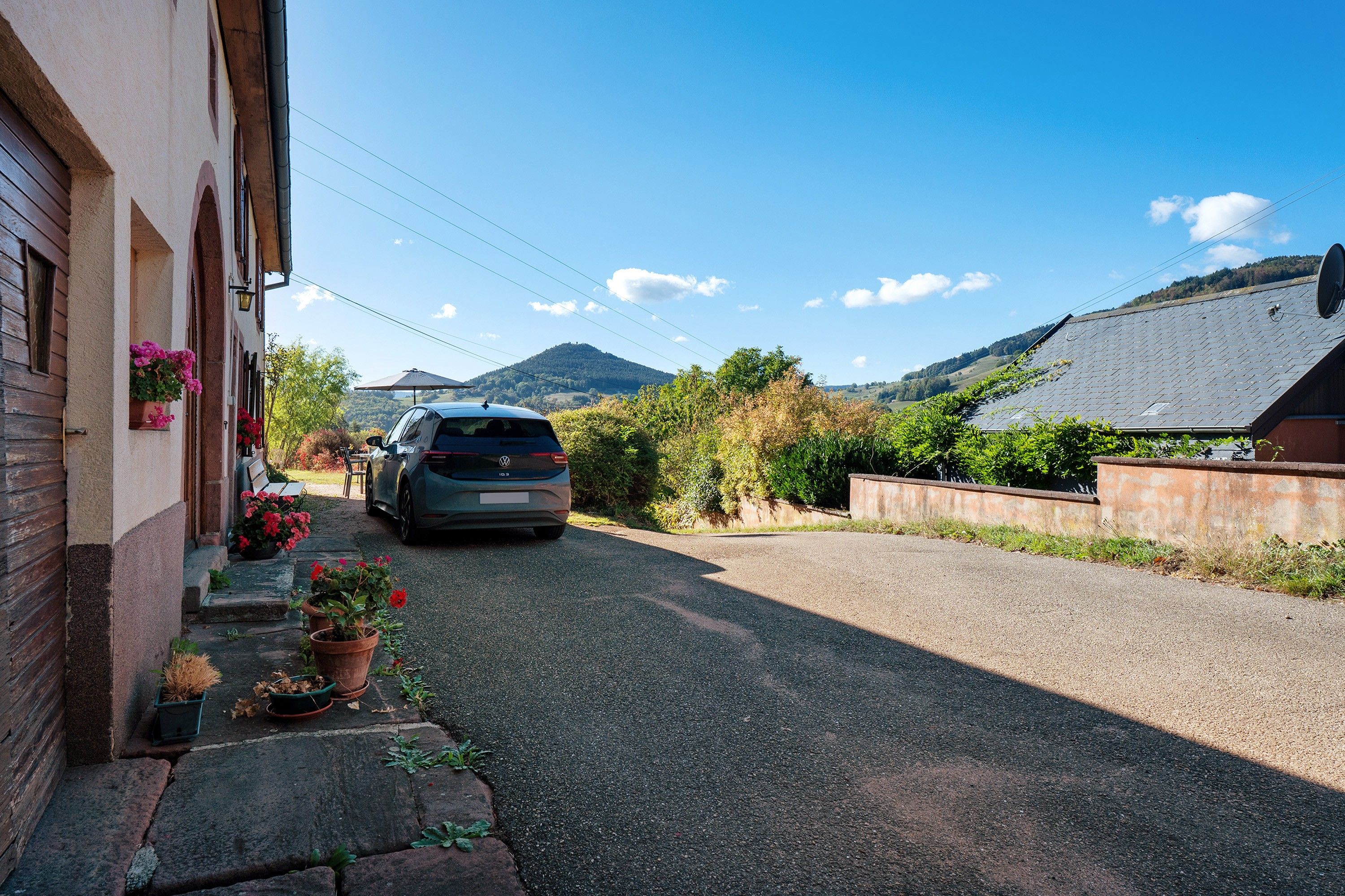 A residential street with a parked car, houses, and a mountain in the background.
