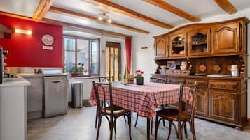 Una cocina con una mesa de comedor, armarios de madera y un reloj de pared rojo.