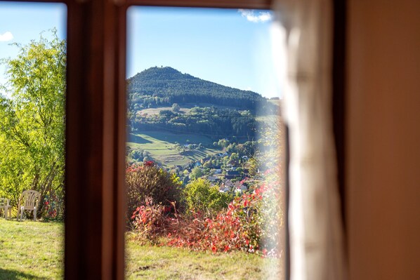A view through a window of a rural landscape with a hill, fields, and a small village.