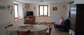 Un salon comprenant une table à manger, un canapé, un téléviseur et un meuble.